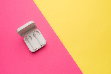 Wireless headphones on a pink background . Bright background. White headphones. Bluetooth headset. Pink and yellow background. Copy space. Modern technologies.