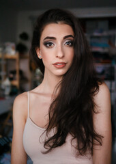 Lifestyle closeup natural light portrait of young pretty thoughtful brunette woman in shoulder straps blouse room domestic background