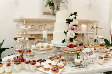 a lovely wedding cake standing among the candy bar. sweet table. banquet table. holiday food. sweet festive table.