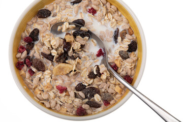 Breakfast oatmeal with nuts and dried fruits in yellow bowl with milk on white background