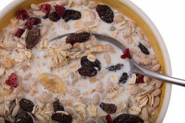 Breakfast oatmeal with nuts and dried fruits in yellow bowl on white