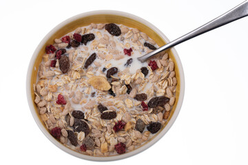 Breakfast oatmeal with nuts and dried fruits in yellow bowl on white