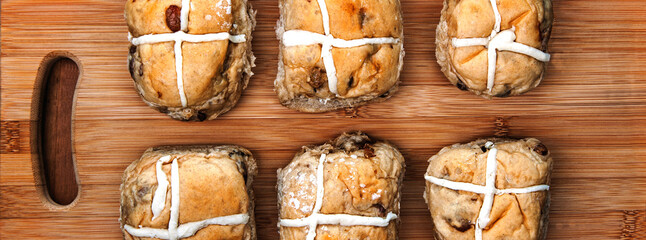 Panorama for traditional, Easter hot cross buns, on a plain, rustic, wooden background.