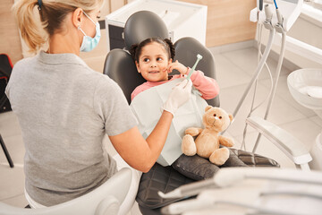 Dentist teaching girl how to brush teeth