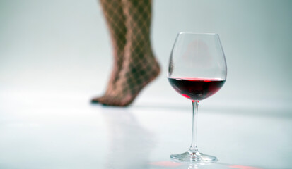 Beautiful girl legs and a glass of alcoholic beverage. Red wine glass. Woman legs. Sexy. Sexual.