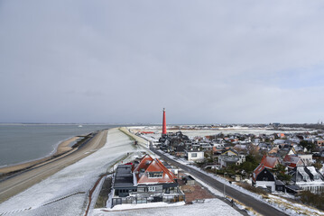 Fototapeta na wymiar The village of Huisduinen with the lighthouse with snow.