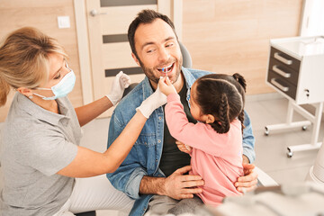 Girl applies a palette with samples to her father's teeth