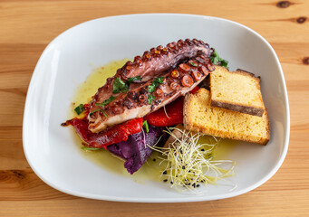 Simple but fancy looking plate of purple sweet potato, pepper and octopus legs with bread toast on the side.