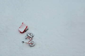Abandoned Children's Bike with Tin Toy Trailer under Snow in the backyard. A Mess in the Yard. Post Apocalyptic.