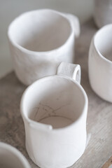 Obraz na płótnie Canvas White handmade clay cups. Tea set on the table. White kitchen items