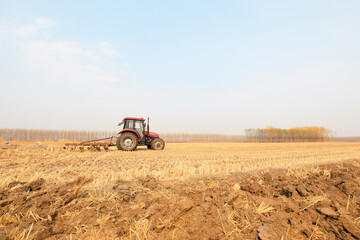 Farmers drive tractors to plow land in farmland, North China