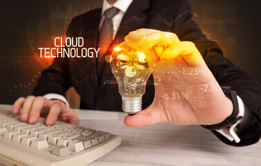 Businessman holding lightbulb with CLOUD TECHNOLOGY inscription, Business technology concept