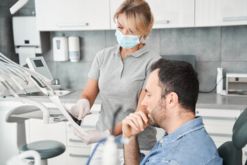 Fototapeta premium Doctor showing a patient his x ray after procedures