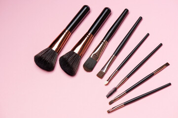 Make up brush sets arranged on pink background, top view with copy space. Cosmetics products.