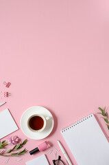 Workplace with notepad, pen, coffee cup and other accessories on pink background