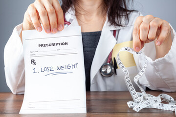 A female physician is holding a prescription that says lose weight in one hand and a tape measure for abdominal circumference measurement on the other. pointing out concepts like diet, overweight etc.
