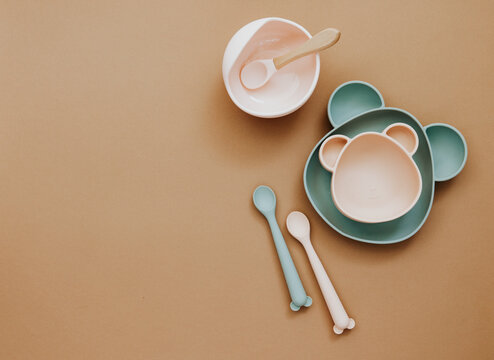 Top view neutral baby cute tableware on brown background, flat lay , copy space