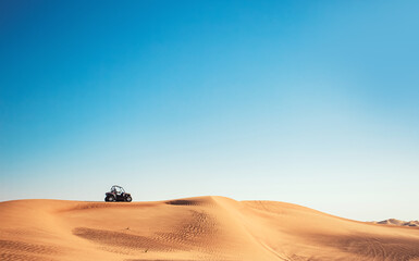 Minimalistic desert view with blue sky, sand hill and one buggy quad bike, motor sport adventures,...