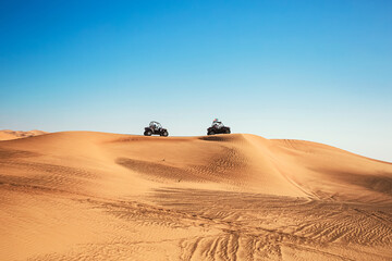 Two buggy quad bikes riding at bright Al Awir desert landscape up on mountain, off-road adventures 
