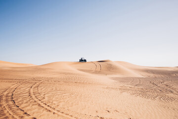 Beautiful desert landscape with wheel traces and black buggy quad bike up on hill, Al awir sand dunes, Dubai, UAE  