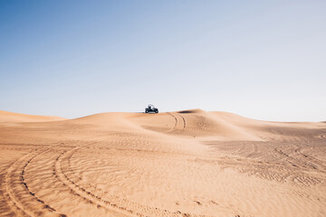 Beautiful desert landscape with wheel traces and black buggy quad bike up on hill, Al awir sand...