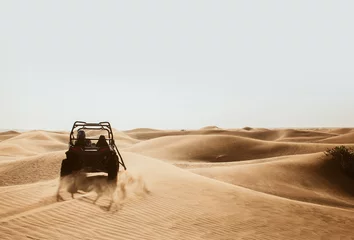 Schilderijen op glas Silhouette of quad buggy bike at left side driving and drifting at safari sand dunes of Al Awir desert, Dubai, UAE, space for text © mynoemy1