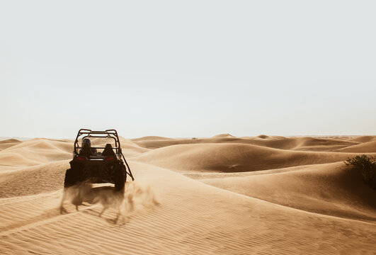 Silhouette of quad buggy bike at left side driving and drifting at safari sand dunes of Al Awir desert, Dubai, UAE, space for text