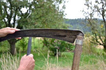 Person Sharpens Scythe Blade