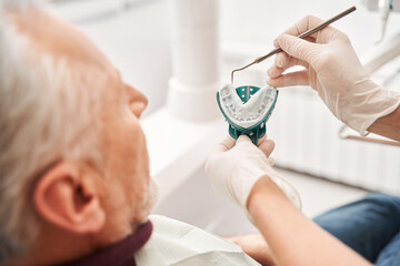 Dentist presenting denture impression to her patient