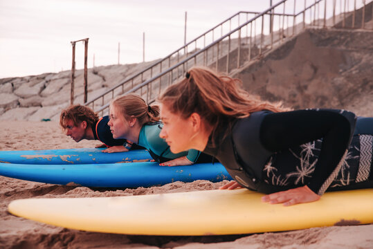 Two young girls and a young boy learning to surf