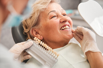 Dentist picking up shade using tooth enamel scale