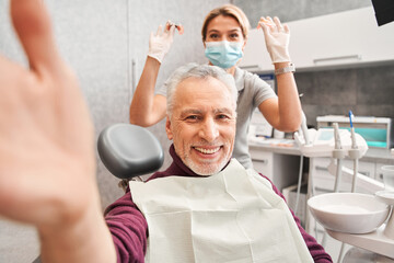 Dentist and patient making selfie in operating room