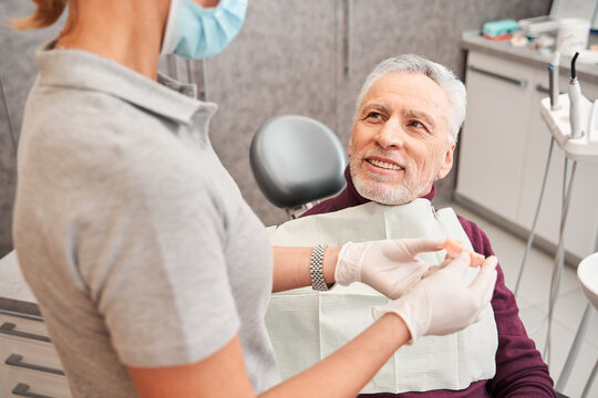 Doctor Holding Dentures Or Artificial Teeth For Man