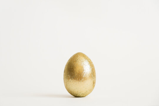 Easter golden glitter egg isolated on white background. Minimal easter concept. Happy Easter card with copy space for text. Top view, flatlay. Concept for banner, flyer, invitation, greeting card
