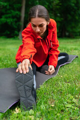 Fototapeta na wymiar girl in the park sitting on a yoga mat doing stretching