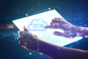 Hand holdig futuristic tablet with SMM inscription, modern technology concept
