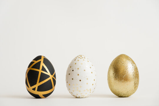 Three Easter golden decorated eggs isolated on white background. Minimal easter concept. Happy Easter card with copy space for text. Top view, flatlay.