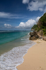 Crystal clear water of a lagoon with waves breaking along a white sand beach in Bali in Indonesia, located on the southern coast of the island.