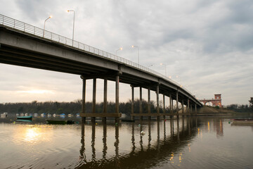 Sol naciente reflajado en el rio, debajo de un puente