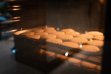 Close up shot of cookies being baked in the oven. 19 biscuits on the top shelf with more under neath it.