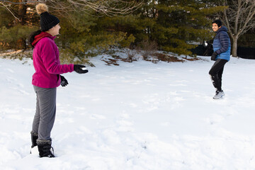 Fototapeta na wymiar Siblings Having a Snowball Fight in Winter