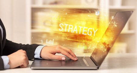 Closeup of businessman hands working on laptop with STRATEGY inscription, succesfull business concept