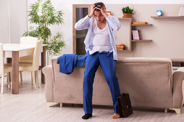 Young male employee getting up late at home