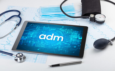 Close-up view of a tablet pc with adm abbreviation, medical concept