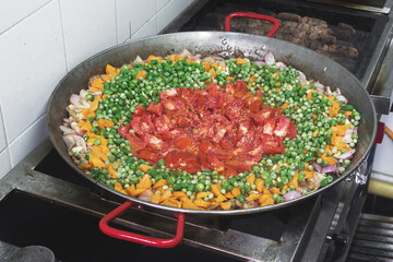 Una olla grande con tomate y habichuelas picados sobre un fogón en una cocina