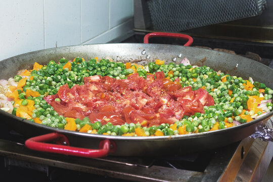 Una olla grande con tomate y habichuelas picados sobre un fogón en una cocina
