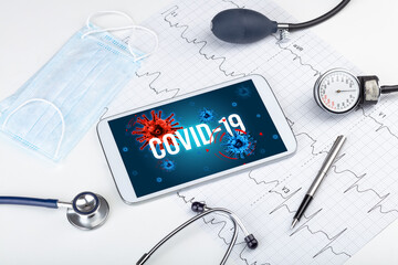 Tablet pc and doctor tools on white surface with COVID-19 inscription, pandemic concept