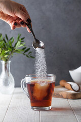 In a cup of tea, pour sugar from a teaspoon. 