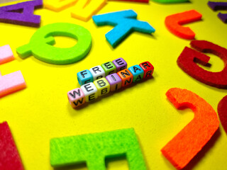 Selective focus.Colorful dice with word FREE WEBINAR on blue background.Education concept.Shot were noise and film grain.