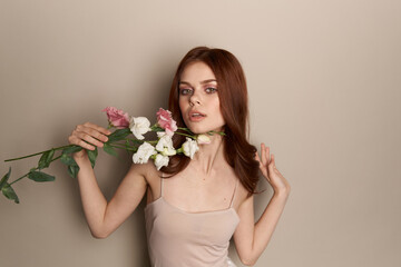Happy woman with a bouquet of light flowers on a beige background naked shoulders model red hair beautiful face